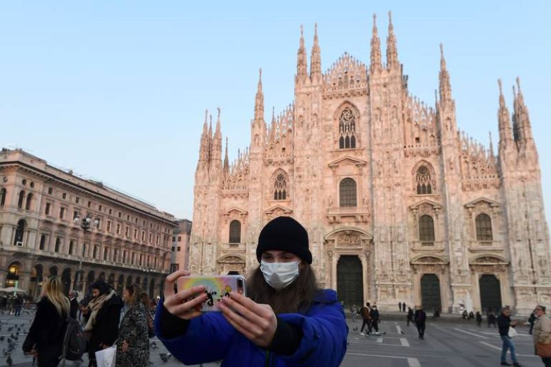 Mulher tira selfie com máscara na Piazza del Duomo, em Milão