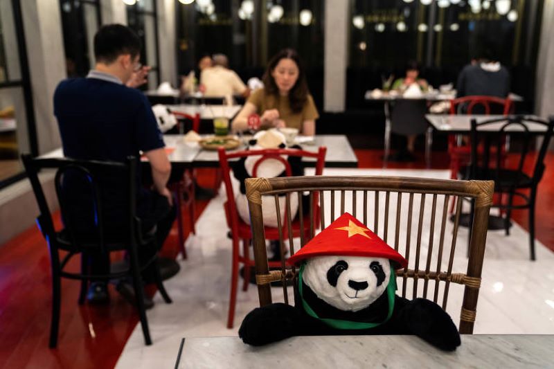 Pessoas jantam sentadas ao lado de pandas de pelúcia em restaurante de Bangcoc