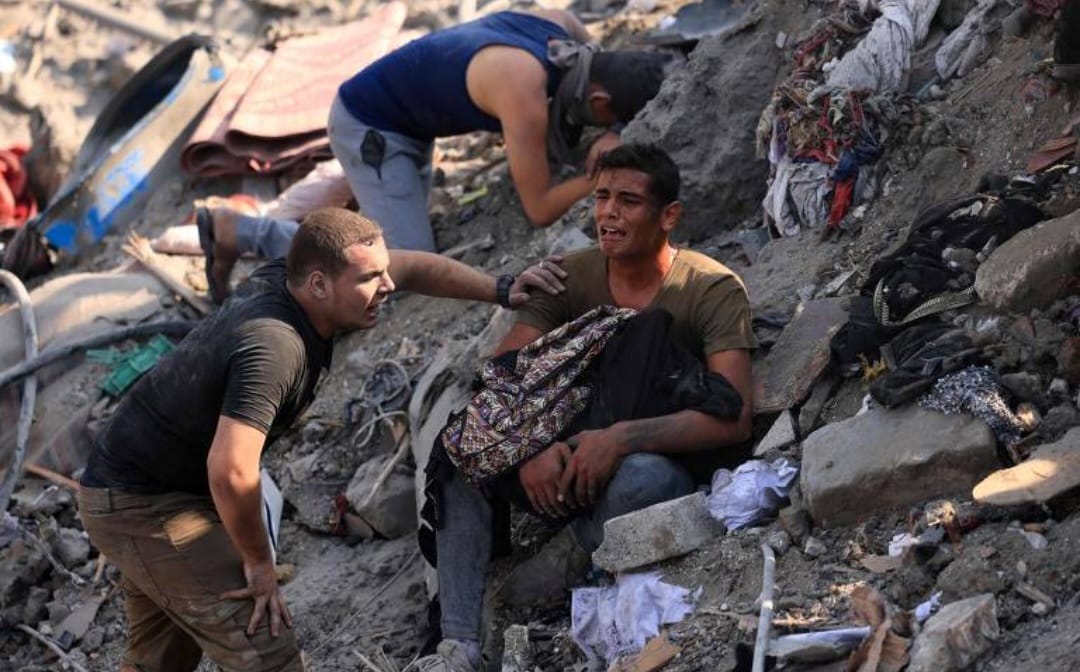 Palestino segura familiar morto em meio a destroços em Bureij, na Faixa de Gaza, em novembro